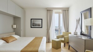 A hotel room with a bed, a desk, a chair, a dresser, and a window with curtains.