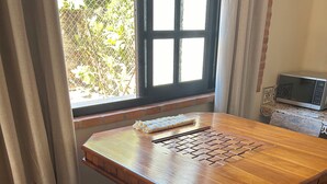 Ein Holztisch mit einer gewebten Tischmatte, ein Stuhl und ein Fenster mit Vorhängen.