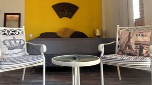 Ein Schlafzimmer mit einem Bett, zwei Stühlen, einem kleinen Tisch und einem Wandbild.