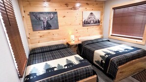 Una habitación con dos camas, un banco, paredes de madera y luces en el techo.