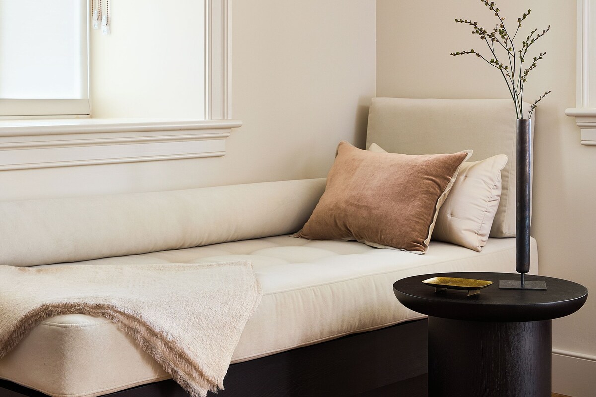 A modern living room with a sofa, a side table, and a vase with a plant.
