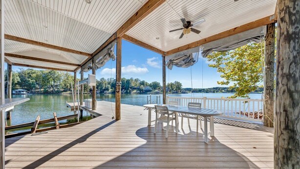 Une terrasse en bois avec une table et des chaises donnant sur un lac.