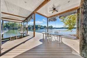 Una terraza de madera con una mesa y sillas, con vista a un lago.