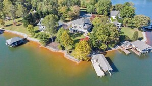 Vue aérienne d’une propriété au bord du lac, comprenant plusieurs maisons, des quais et un bateau.