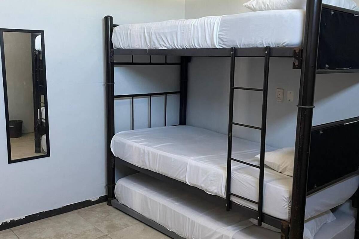 A bunk bed with two levels, a mirror on the wall, and tiled flooring.