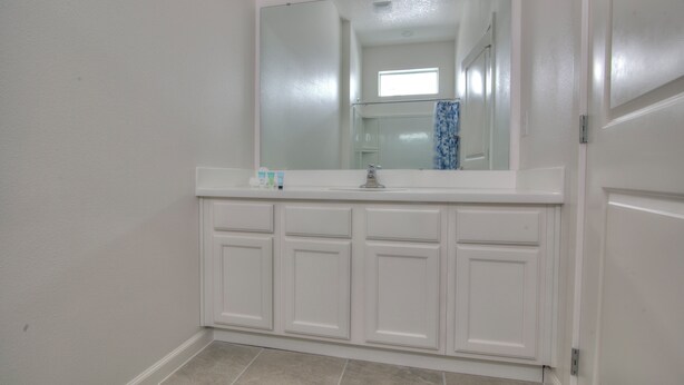 A bathroom with a white vanity, a mirror, and a tiled floor. - Hotel Styled Bedrooms in a Villa (Kissimmee)