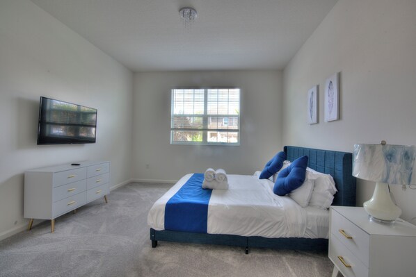 A bedroom with a bed, a dresser, a TV, and a window.