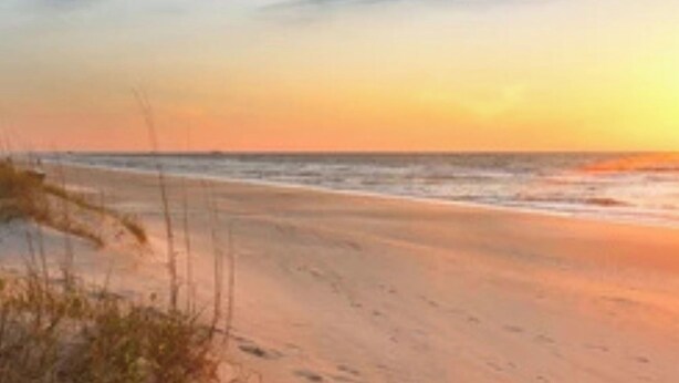 Ein Strand mit blauem Himmel und sanften Wellen.