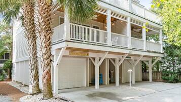Stylish two-story retreat with a balcony and garage door, set amidst a palm tree and a driveway.