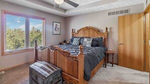 A bedroom with a wooden four-poster bed, a ceiling fan, a window with blinds, and a door. - Charming 2-bedroom house in lovely Omaha with AC, WiFi. (Omaha)