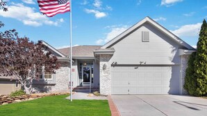 A two-story house with a stone facade, a garage, and a well-maintained lawn. - Charming 2-bedroom house in lovely Omaha with AC, WiFi. (Omaha)