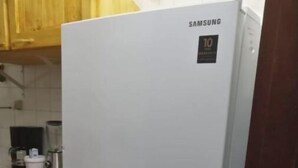 Et Samsung-køleskab i et køkken med træskabe og en bordplade.