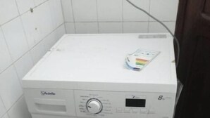 En kompakt, hvid vaskemaskine med frontåbning, et kontrolpanel og en lille brugsanvisning ovenpå.