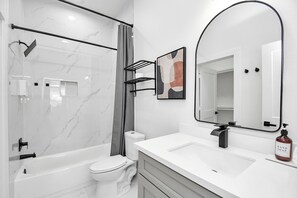 A modern bathroom with a bathtub, toilet, and vanity with a mirror.