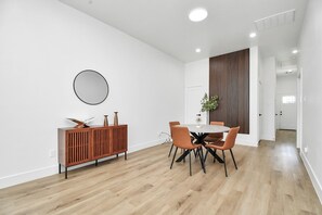 A modern dining area with a wooden cabinet, a round mirror, and a dining table with chairs.