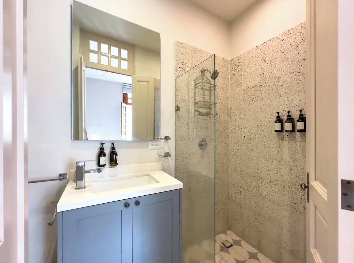 Un baño moderno con ducha de vidrio, un lavabo blanco y un espejo encima.