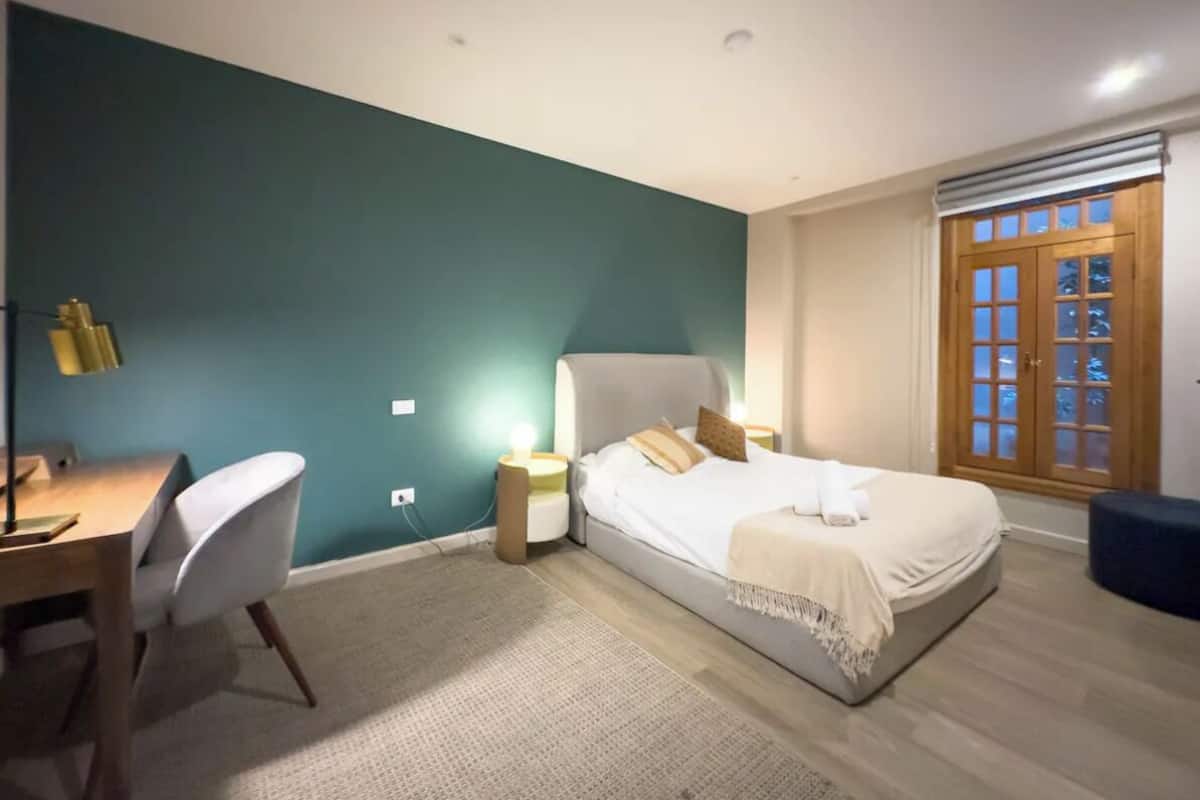 A bedroom with a bed, bedside tables, a desk, and a chair.