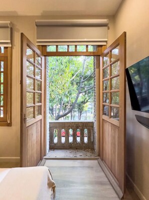 A hallway with a wooden door leading to a balcony with a view of trees. - Lasai Casa Puebla  (Mexico City)