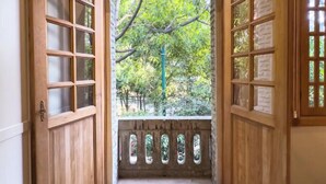 A room with a wooden door leading to a balcony with a view of trees. - Lasai Casa Puebla  (Mexico City)