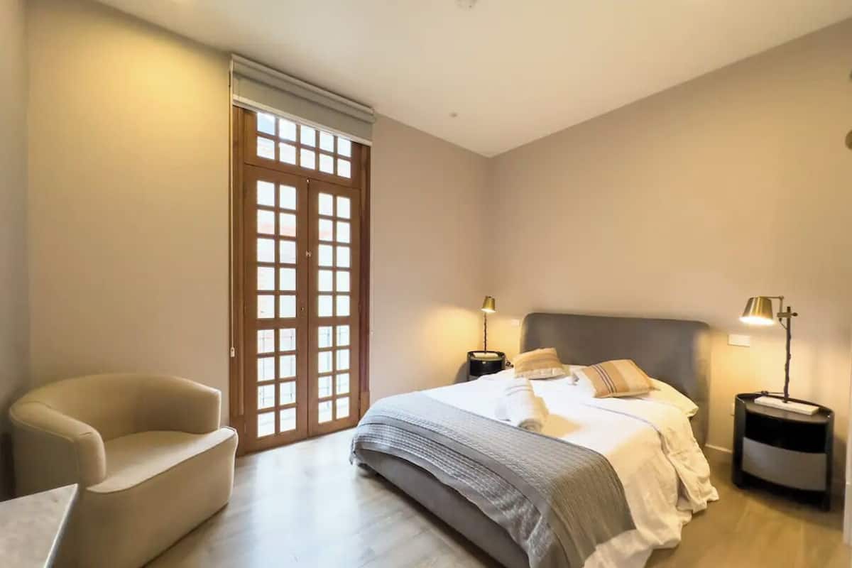 A bedroom with a bed, bedside tables, a chair, and a sliding door.