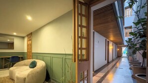 A corridor with a seating area, a wooden door, and potted plants. - Lasai Casa Puebla  (Mexico City)