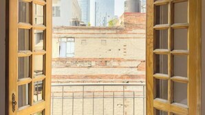 A view through a wooden-framed door with glass panels, leading to a balcony with a metal railing. - Lasai Casa Puebla  (Mexico City)