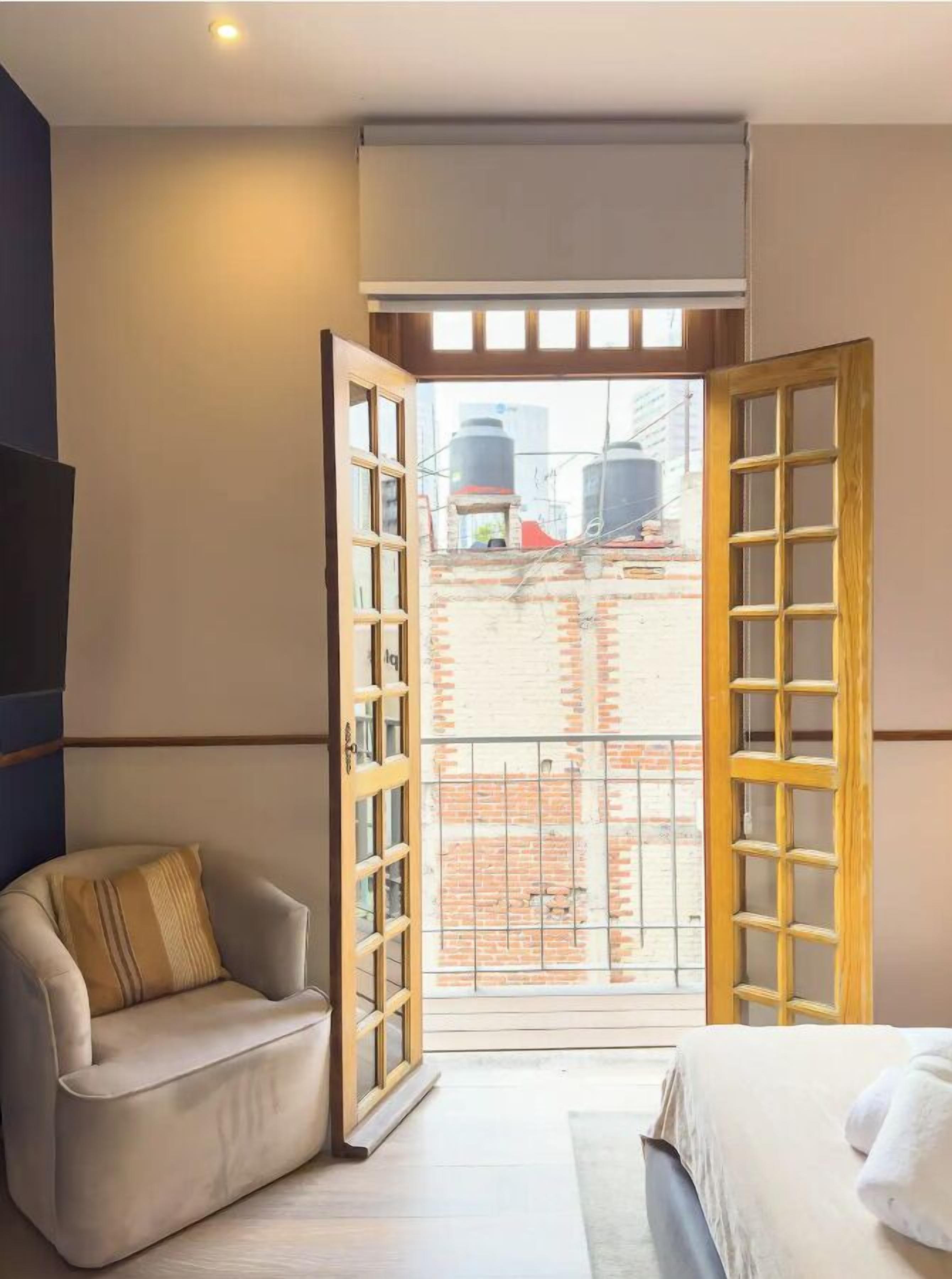 Ein Zimmer mit einem Bett, einer Couch und einem großen Fenster mit Blick auf Industriegebäude.