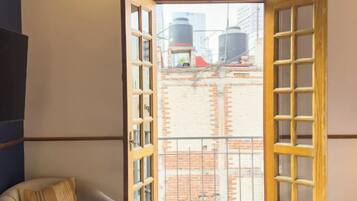 Ein Zimmer mit einem Bett, einer Couch und einem großen Fenster mit Blick auf Industriegebäude.