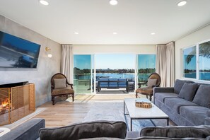 Uma sala de estar moderna com lareira, assentos confortáveis e uma grande janela com vista para o mar.