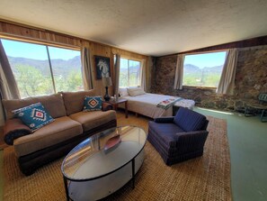 Relax in this inviting room with a comfortable sofa, a neatly made bed, and a scenic view of the surrounding landscape.