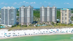 Un hotel frente a la playa con varios edificios altos, una playa de arena y un cielo azul despejado.