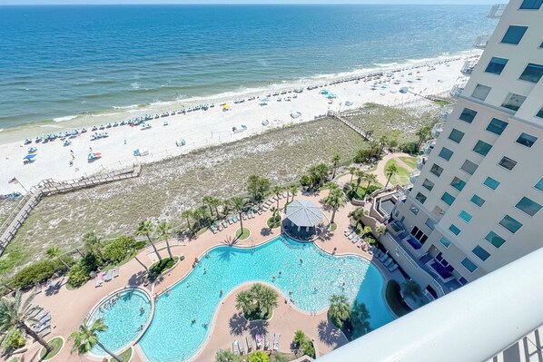 A resort with a beach, a pool area, and a building with balconies.