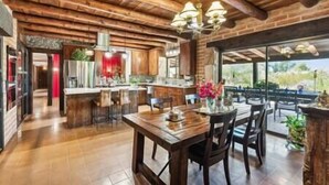 A spacious kitchen with wooden beams, a dining area with a table and chairs, and a large window offering a view of the outdoors. - "Scarritt House"  Small Deluxe Blue Bedroom. (Tucson)