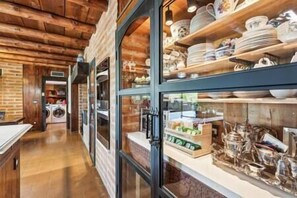 A corridor with wooden walls and a glass display case filled with dishes and kitchenware.