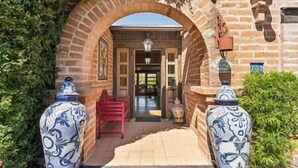An entrance with a brick archway, a red chair, and two decorative vases. - "Scarritt House"  Small Deluxe Blue Bedroom. (Tucson)
