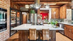 A spacious kitchen with a large island, wooden cabinets, and a brick wall. - "Scarritt House"  Small Deluxe Blue Bedroom. (Tucson)