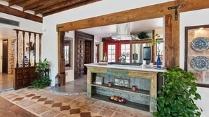 A spacious kitchen with a stone floor, wooden beams, and a central island with fruit. - Rancho Bonito "Beautiful Ranch" (Tucson)