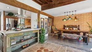 A kitchen with a rustic design, featuring exposed brick walls, wooden beams, and a stone floor. - Rancho Bonito "Beautiful Ranch" (Tucson)