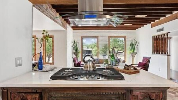 A modern kitchen with a central island, wooden beams, and large windows. - Rancho Bonito "Beautiful Ranch" (Tucson)
