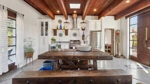 Une cuisine spacieuse avec une grande table en bois, des armoires blanches et un luminaire suspendu moderne.