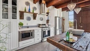 Une cuisine moderne avec des meubles blancs, des appareils en acier inoxydable et une table à manger en bois.