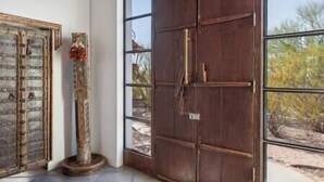 Une pièce dotée d’une grande porte en bois et d’une fenêtre donnant sur la végétation désertique.