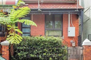 A residential building with a red brick facade, a tiled roof, and a small front garden with a metal gate. - The Newtown Nest (Newtown)