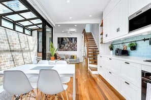 Una cocina moderna con armarios blancos, un salpicadero azul y una escalera de madera.