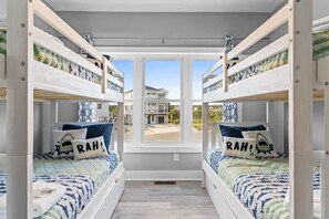 Habitación con literas y vista a una casa a través de una ventana.