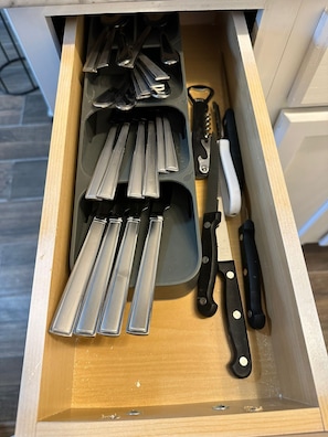 A drawer containing various kitchen utensils and tools, including knives, a spatula, and a grater. - DEPARTAMENTO PARA 5 (Ciudad Juárez)