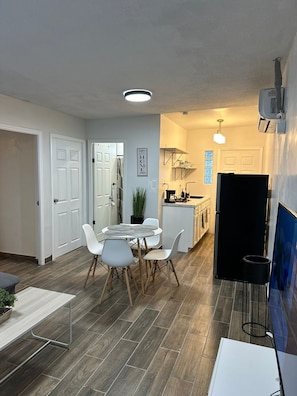 A modern kitchen with white cabinets, a black refrigerator, and a dining area with a round table and white chairs. - DEPARTAMENTO PARA 5 (Ciudad Juárez)