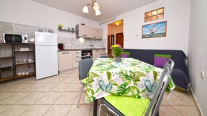 A compact kitchen with a dining area, a microwave, a refrigerator, and a table with a floral tablecloth. - Apartment 2366/123283 (Istria - Rovinj), 1500m from the beach (Rovinj)