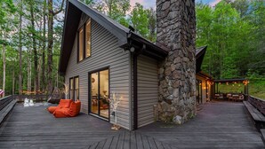 A modern cabin with a stone exterior, a deck, and a cozy seating area.