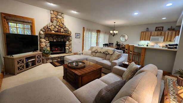 Una sala de estar acogedora con chimenea de piedra, televisor y asientos cómodos.